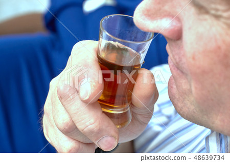 A man sniffing cognac in a glass, defocus close-up 48639734
