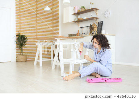 Woman moving into new apartment house assembling Woman moving into new apartment house assembling 48640110
