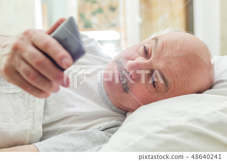 An elderly man turns off the alarm on the phone 48640241