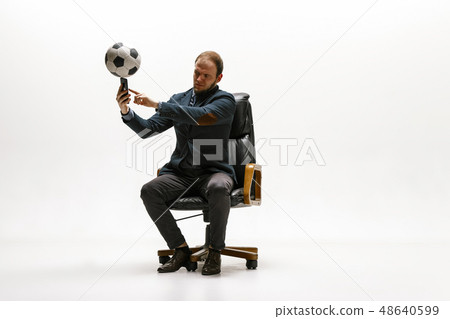 Businessman with football ball in office Businessman with football ball in office 48640599
