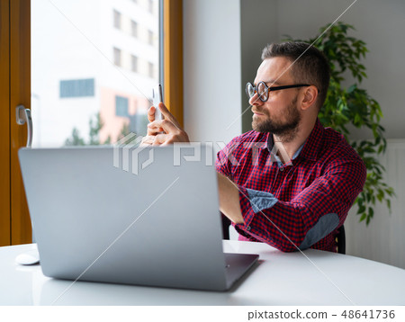 Man in glasses sitting at home office and working Man in glasses sitting at home office and working 48641736
