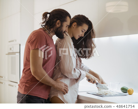 Smiling young couple cooking food in the kitchen Smiling young couple cooking food in the kitchen 48641754