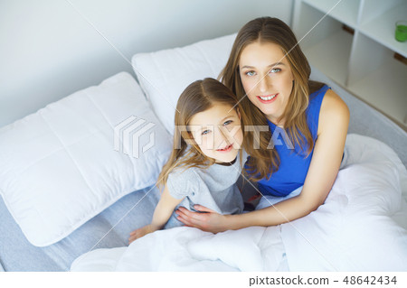 Young woman playing with little girl on bed 48642434