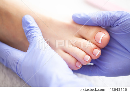 Hand and Nail Care. Beautiful Women's Feet with Pedicure in Beauty Salon. Master Doing Massage Feet Hand and Nail Care. Beautiful Women's Feet with Pedicure in Beauty Salon. Master Doing Massage Feet 48643526