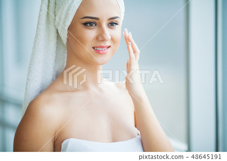 A beautiful woman using a skin care product, moisturizer or lotion and Skincare taking care of her A beautiful woman using a skin care product, moisturizer or lotion and Skincare taking care of her 48645191