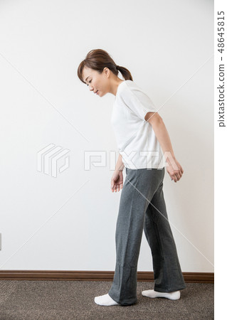 A woman walking with a bad posture 48645815