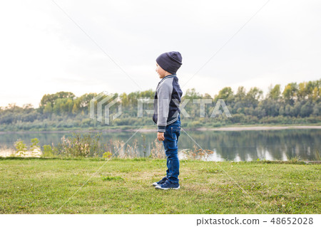 Children and childhood concept - young boy walking near the river 48652028