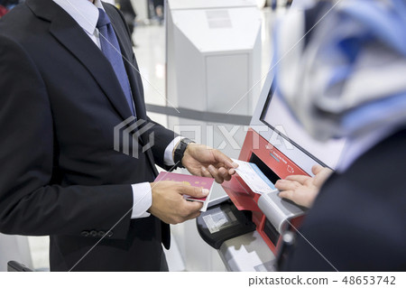 Businessman being instructed on how to use an automatic check-in machine at the airport 48653742