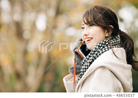 穿外套的一名年輕日本婦女談話與一個聰明的冬天冬天公園 48655037