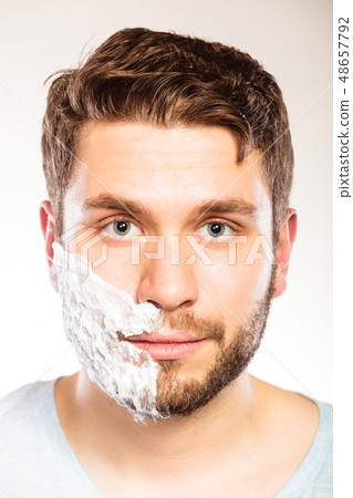 Man with shaving cream foam on half of face. Man with shaving cream foam on half of face. 48657792