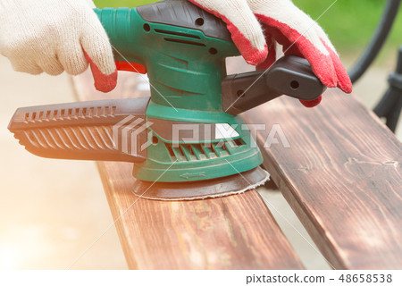 Sanding a wood with orbital sander 48658538