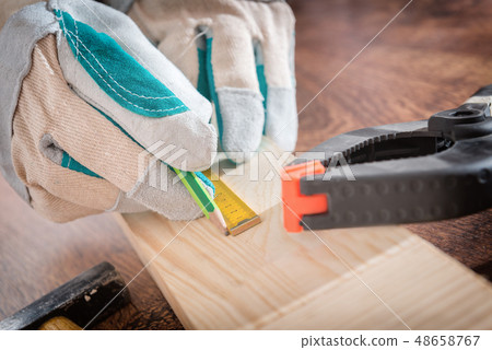 Carpenter measuring a wooden plank 48658767
