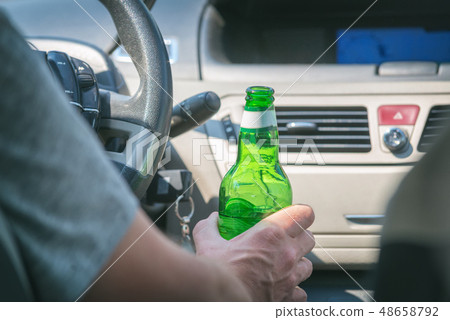 Man drinking beer while driving a car Man drinking beer while driving a car 48658792