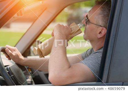 Man drinking alcohol while driving a car 48659079