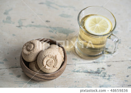 Glass of herbal tea and cookies on a wooden table 48659836