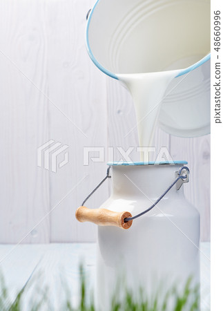 pouring milk from a bucket 48660996