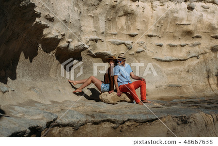 Couple in sunglasses sitting on stone on the 48667638