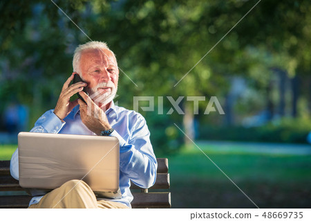 Business correspondence. Focused mature businessman using laptop while sitting in park 48669735