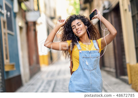 Attractive African girl listening to music with Attractive African girl listening to music with 48672785