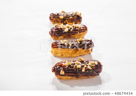 Food, bakery and desserts concept - row of eclairs on white background Food, bakery and desserts concept - row of eclairs on white background 48674434