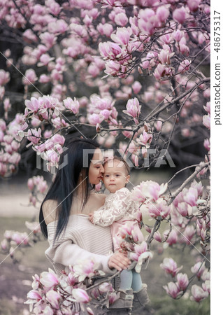 Cute Baby 6 month old Girl in Pink Outfit with Big Blue Eyes with Young Beautiful Mother at Spring Cute Baby 6 month old Girl in Pink Outfit with Big Blue Eyes with Young Beautiful Mother at Spring 48675317