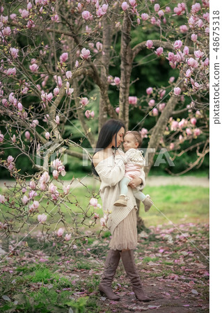 Young mother and little daughter in autumn park play with magnolia leaves. Happy weekend with family Young mother and little daughter in autumn park play with magnolia leaves. Happy weekend with family 48675318