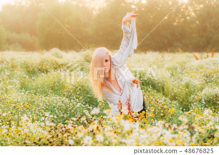 Portrait of young girl dancing in chamomile field 48676825
