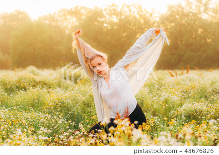 Portrait of young girl dancing in chamomile field Portrait of young girl dancing in chamomile field 48676826