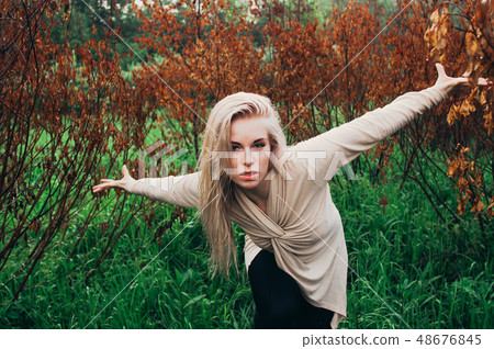 Portrait of young girl dancing between dead trees 48676845