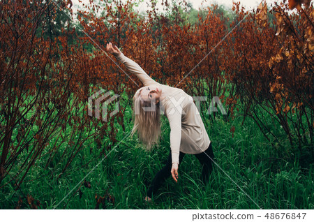 Portrait of young girl dancing between dead trees 48676847
