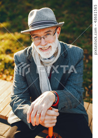Elegant old man in a sunny autumn park Elegant old man in a sunny autumn park 48681565