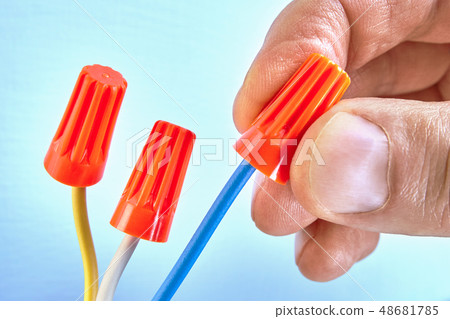 Electrician holds wire connectors on wires. 48681785