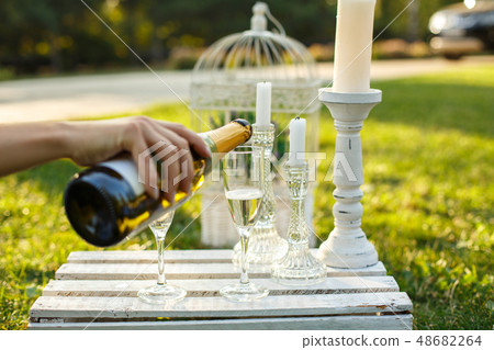 Woman pours champagne from bottle to glass on Woman pours champagne from bottle to glass on 48682264