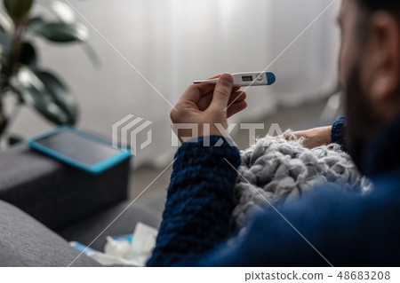 Selective focus of a thermometer in male hands 48683208