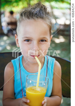 beautiful boy is drinking orange juice  48684254