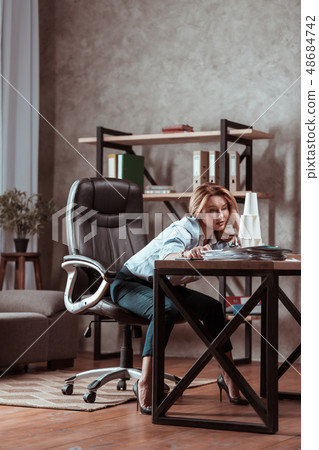 Woman wearing high heels sitting at the table feeling concerned 48684742