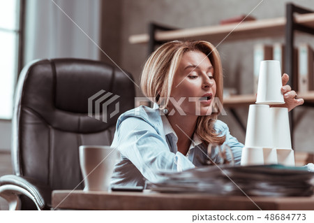 Woman feeling bored at work building pyramid from glasses 48684773