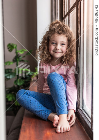 Charming curly-haired girl looking straight at camera Charming curly-haired girl looking straight at camera 48686242