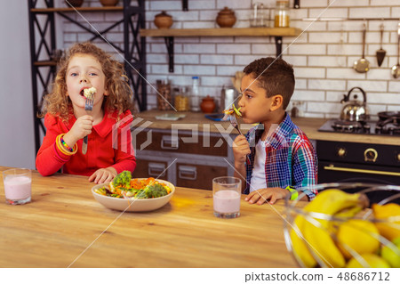 Concentrated kids enjoying their bowl of fresh salad 48686712