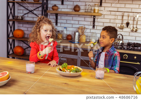 Pleased brunette kid having dinner with his sister 48686716