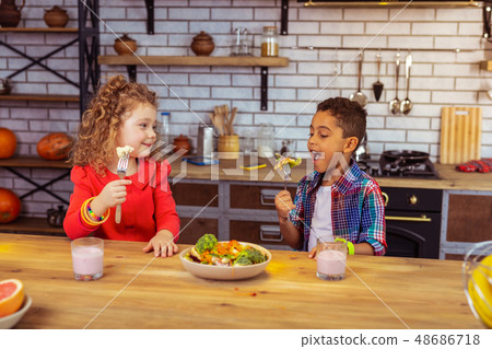 Hungry international boy eating vegetables with pleasure 48686718