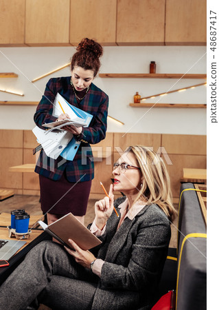 Blonde-haired businesswoman giving tasks to young helpful secretary Blonde-haired businesswoman giving tasks to young helpful secretary 48687417