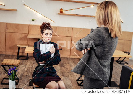 Young trainee feeling worried listening to her strict female boss Young trainee feeling worried listening to her strict female boss 48687519