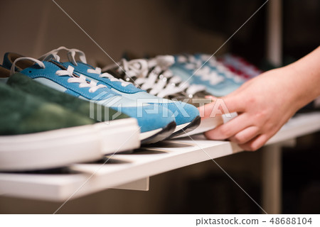 Female hands put sneakers collection on store rack Female hands put sneakers collection on store rack 48688104