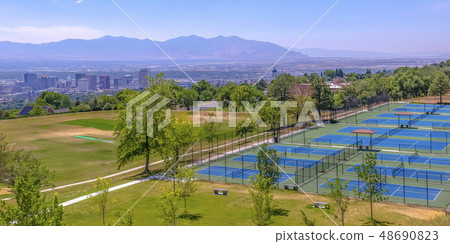 Sunlit tennis courts with city and mountain view Sunlit tennis courts with city and mountain view 48690823