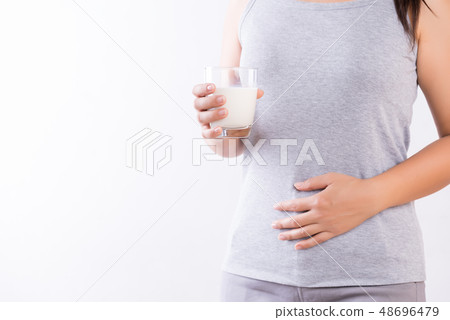 Woman holding glass of milk having stomachache 48696479