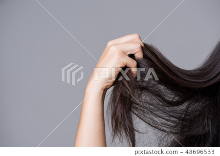 Woman hand holding damaged long hair. Woman hand holding damaged long hair. 48696533
