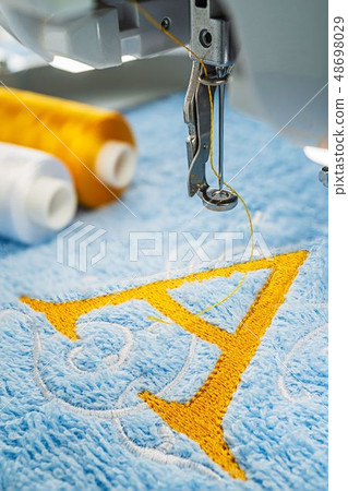 Embroidery machine and alphabet logo on towel Embroidery machine and alphabet logo on towel 48698029