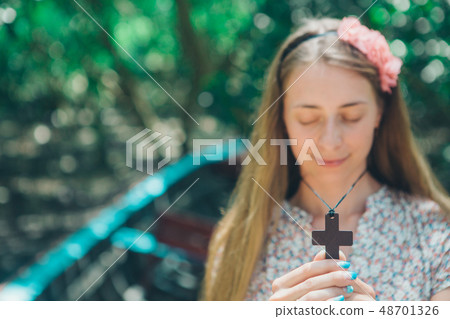 cross in the hands of a girl close-up, portrait of 48701326