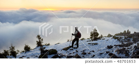 Tourist with backpack hiking on rocky mountain peak on background of foggy valley and blue sky at Tourist with backpack hiking on rocky mountain peak on background of foggy valley and blue sky at 48701653